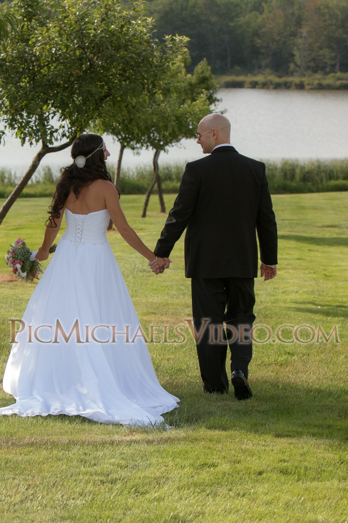 The bride and groom take an outdoor stroll to the rustic lakeside.