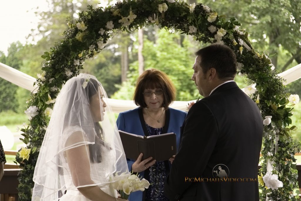 Bride and groom recite their vows under floral arch